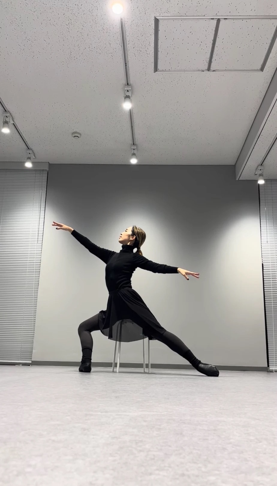 スタジオで腕を大きく広げて踊る大人の生徒