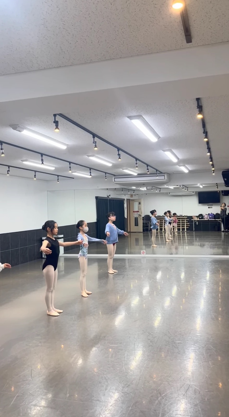 スタジオの中央で腕のポジションを練習する子どもたち